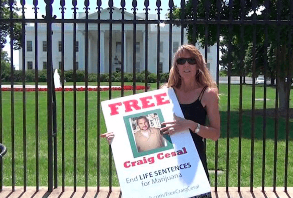 Amy Ralston Povah holding a picture of Craig Cesal outside the White House