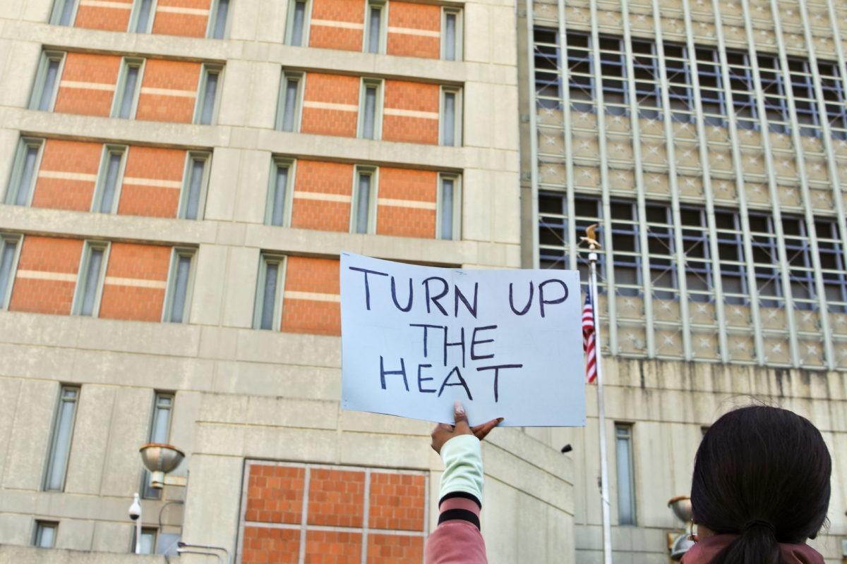 a protester holds a sign outside the Metropolitan Detention Center to protest conditions inside the jail.