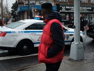 People walk past a police car in the in the Brownsville neighborhood of Brooklyn on November 18, 2019 in New York City.