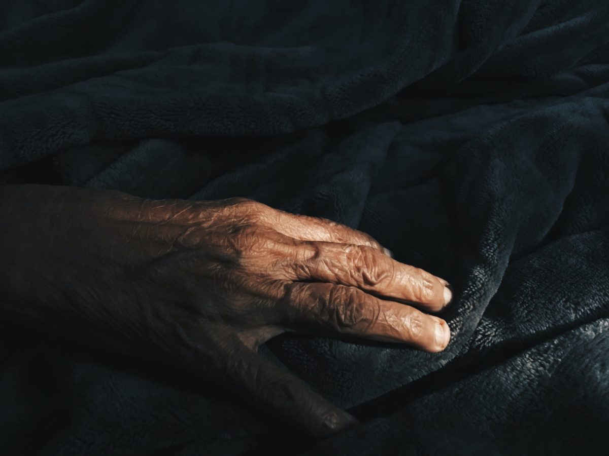 elderly person's hand on dark background
