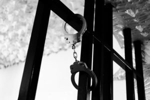 greyscale image of handcuffs on steel bars