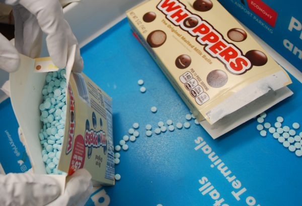 A photo from the Los Angeles County Sheriff's Department showing small, teal fentanyl pills hidden in a Whoppers malted milk ball candy box.