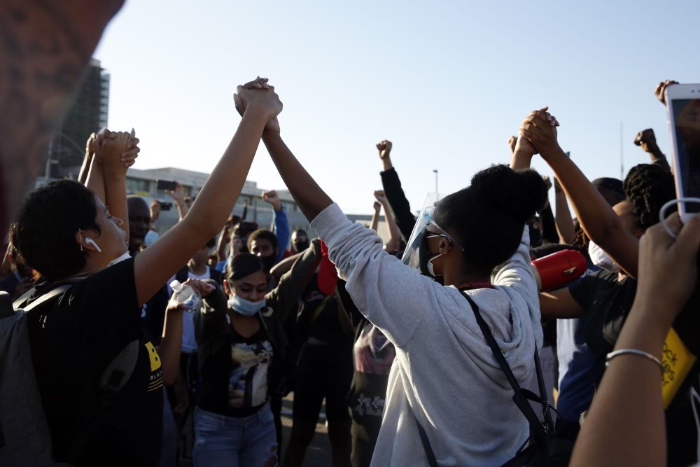 Megan Castillo with hands raised in the air alongside other Black Lives Matter activists at a people's uprising demanding that LA County and the world value Black Life. May, 2020.