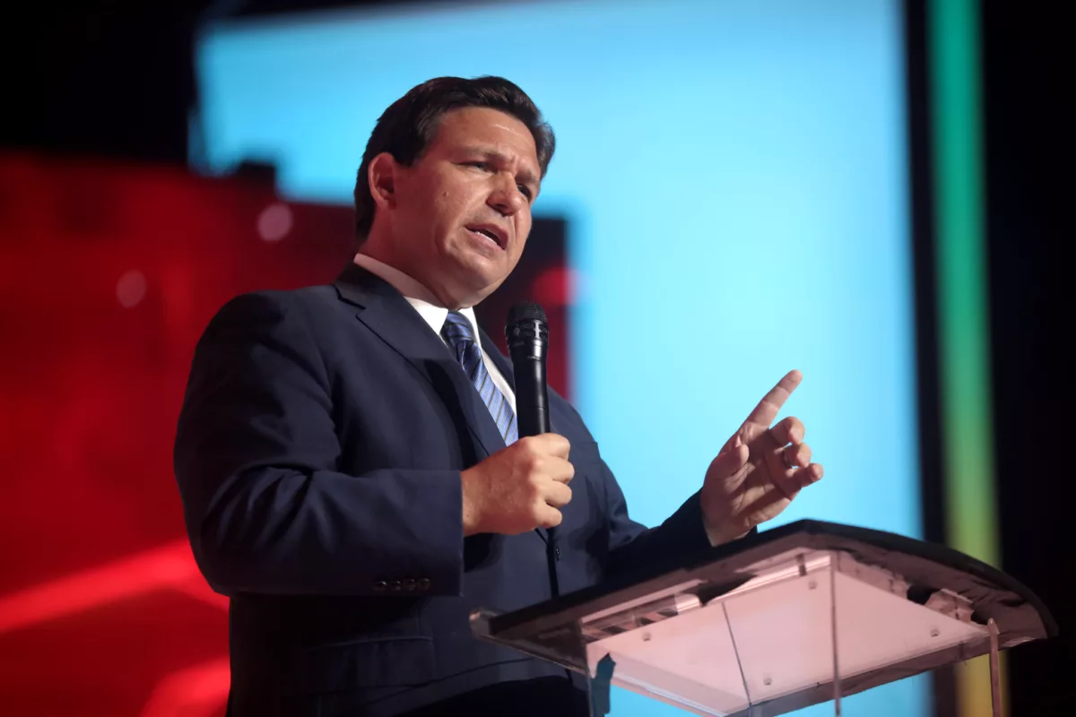 Ron DeSantis stands at a lectern on a stage giving a speech.
