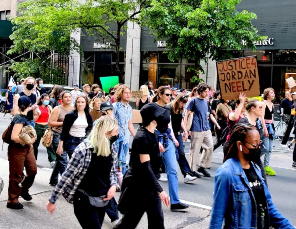 This photo shows a crowd marching during a protest in New York City over the death of Jordan Neely. One protester holds a sign that says "Justice for Jordan Neely."