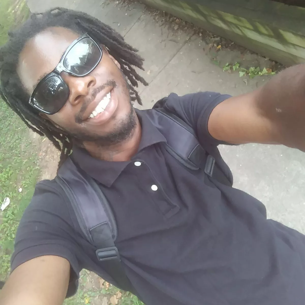 This photo shows Antonio Meanus taking a selfie. He is wearing black sunglasses and a black polo shirt.