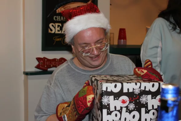 This photo shows Anthony Talotta wearing a Santa Claus hat and opening a present during Christmastime.