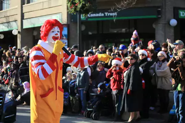 This photo shows a man dressed as Ronald McDonald speaking into a microphone during a parade.