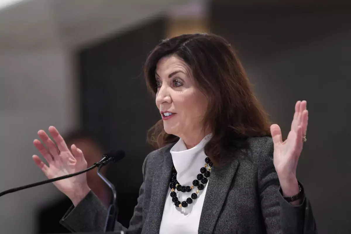 This photo shows NY Gov. Kathy Hochul waving her hands at a lectern.