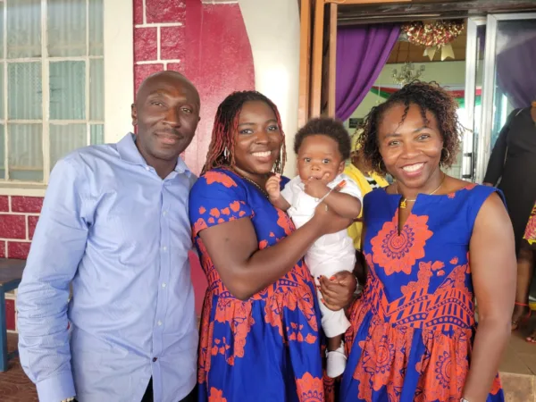 Photo of three adults and a baby, everyone wearing blue—Samuel, his cousin Pam holding daughter Saharan, and Samilia in 2022 in Freetown, Sierra Leone.