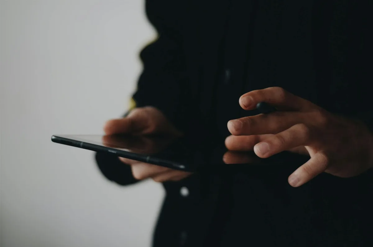 This photo shows a zoomed-in image of a person's hands holding a tablet-sized device.