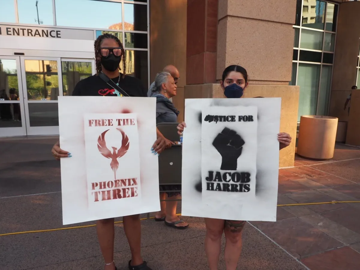 Protesters holding signs demanding the release of three youths incarcerated for a murder committed by a police officer.