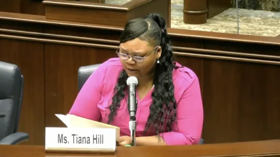 This photo shows Tiana Hill, in a pink, long-sleeve shirt, testifying in front of U.S. Senator Jon Ossoff in Washington, D.C.