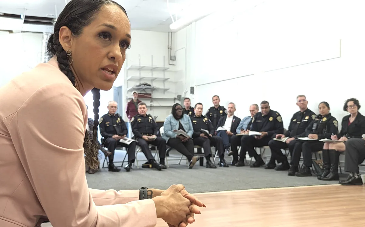 This photo shows San Francisco District Attorney Brooke Jenkins sitting in a circle surrounded by members of law enforcement.