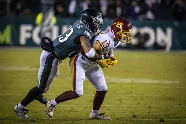 This photo shows Philadelphia's Lincoln Financial Field football stadium. A Philadelphia Eagles player is tackling a Washington Commanders player, who holds a football.