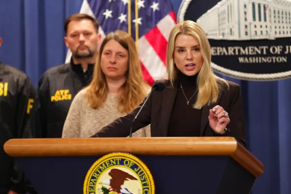 This photo shows Attorney General Pam Bondi speaking at a lectern during a press conference.