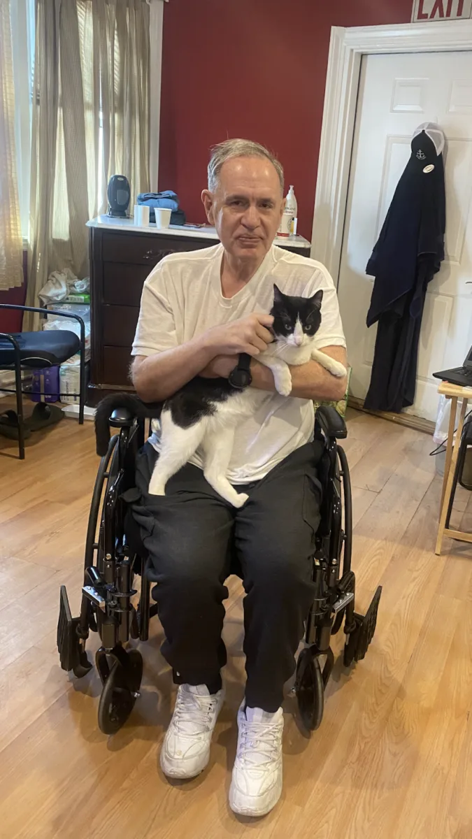 James Carver sits with a cat in his wheelchair in his room at the residential-care home where he is living after his release from prison.