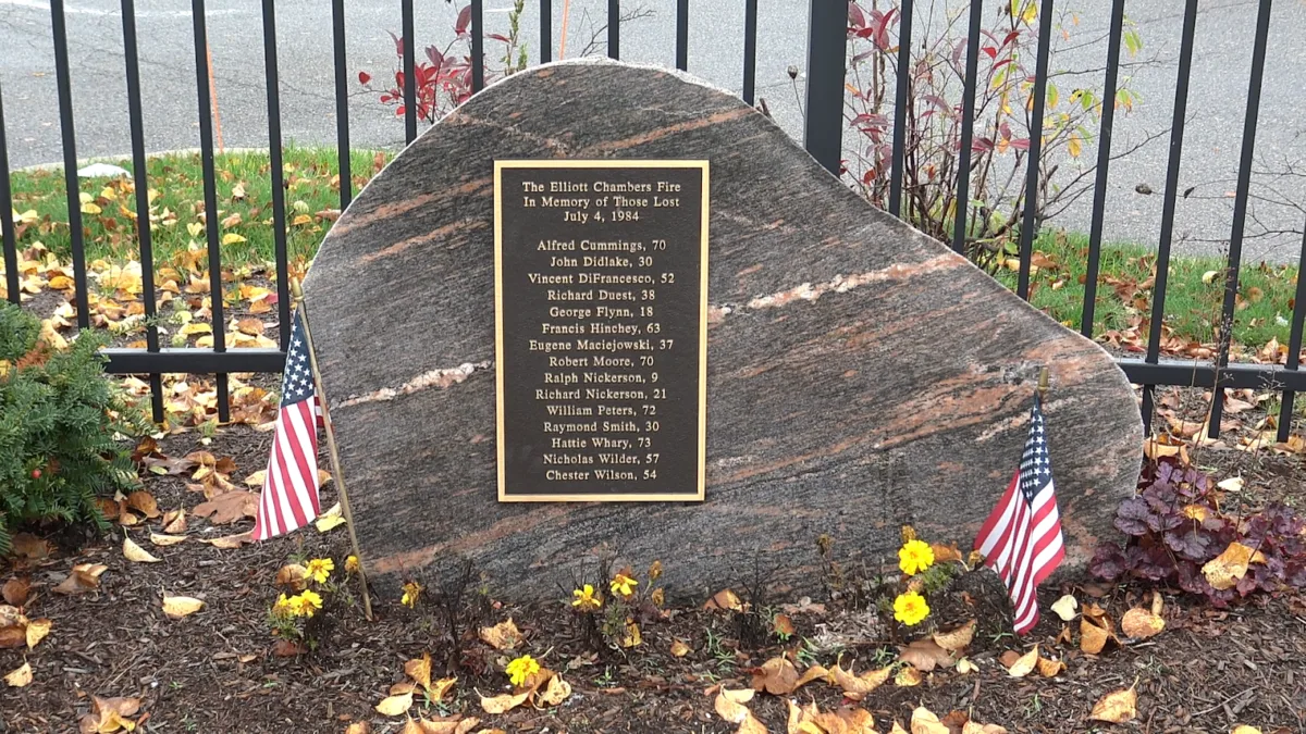 A granite monument, with a plaque listing the names and ages of the 15 people who were killed by the Elliott Chambers Rooming House fire, sits outside the CVS located at the site once occupied by the rooming house.